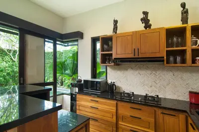 a kitchen with wooden cabinets and a black counter top at Villa Uma Sari - 2BDR, Private Pool and Sunset Rooftop, Quiet and Central in Seminyak