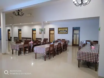 a dining room with tables and chairs and a chandelier at Rumah Retret Bethania in Kuta