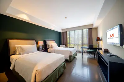 a hotel room with two beds and a flat screen tv at Swiss-Belhotel Rainforest in Kuta