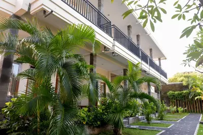 a building with palm trees in front of it at Puri Panca Jaya Hotel in Seminyak