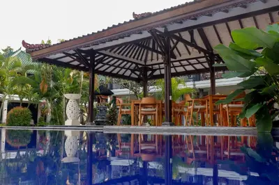a patio with a table and chairs next to a pool at Puri Panca Jaya Hotel in Seminyak