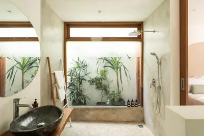 a bathroom with a black tub and plants on the wall at House of Bagera by Alfred in Bali in Seminyak