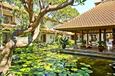 a garden with a pond with lily pads in front of a house at Bali Rani Hotel in Kuta