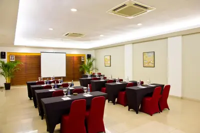 a conference room with tables and red chairs and a screen at Bali Rani Hotel in Kuta