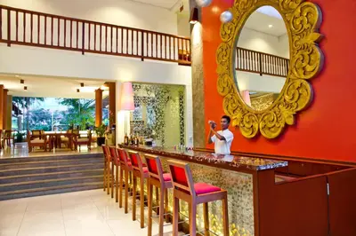 a woman standing at a bar with a mirror at The Rani Hotel & Spa in Kuta