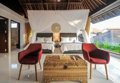 a bedroom with two beds and two red chairs at Villa Pearl Seminyak in Seminyak