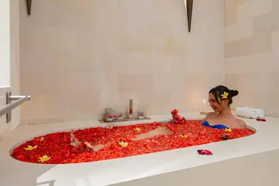 a woman laying in a bath tub covered in red peppers at Luxury - Villa K - Central Seminyak in Seminyak