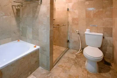 a bathroom with a toilet and a shower and a tub at Hotel Kumala Pantai in Legian