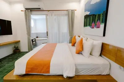 a bedroom with a large bed with orange and white pillows at Brown Feather Batu Belig in Seminyak