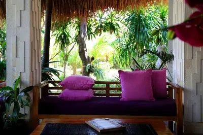 a bench with three purple pillows on a porch at Kaniya bali in Nusa Dua