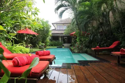 a swimming pool with red furniture next to a house at Villa Casa Bali - your home away from home in Seminyak