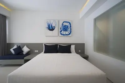 a bedroom with a white bed and a blue couch at The Rooms Apartment Bali by ARM Hospitality in Denpasar