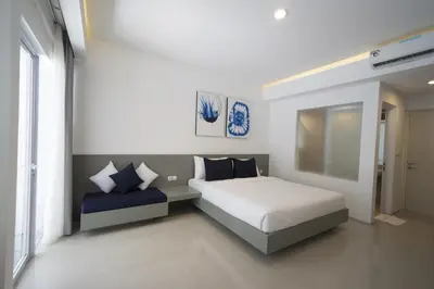 a white bedroom with a bed and a window at The Rooms Apartment Bali by ARM Hospitality in Denpasar