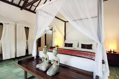 a bedroom with a bed with two statues on a table at Villa Jumah in Seminyak