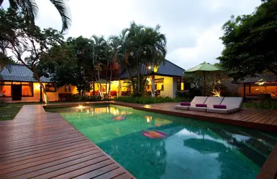 a swimming pool with two lounge chairs next to a house at Villa Jumah in Seminyak