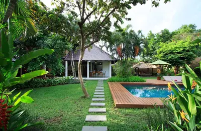 a garden with a swimming pool and a house at Villa Jumah in Seminyak