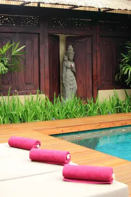 a pool with two pink pillows in front of a building at Villa Jumah in Seminyak