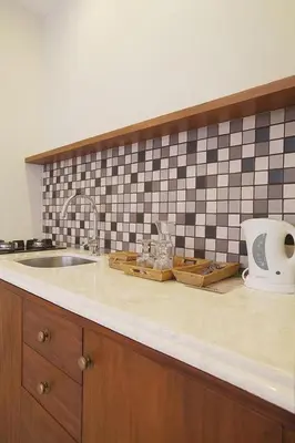a kitchen counter with a sink and a tiled wall at Seminyak Lagoon All Suites Hotel in Seminyak