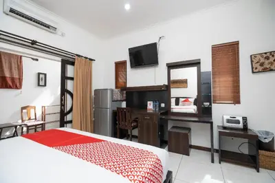 a bedroom with a bed and a desk with a computer at Hotel O Panen House in Seminyak