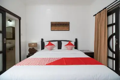 a bedroom with a large bed with red and white pillows at Hotel O Panen House in Seminyak