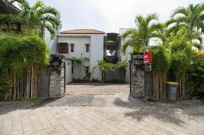 a gate to a house with palm trees in front of it at Hotel O Panen House in Seminyak