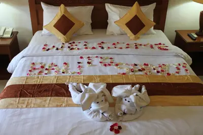 a bed with two towels and flowers on it at Bali Sandy Resort in Kuta