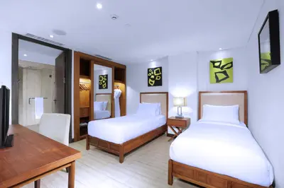 a hotel room with two beds and a desk at Lv8 Resort Hotel in Canggu