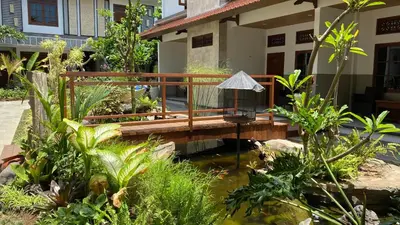 a wooden bridge over a pond in front of a house at Sandat Hotel Legian in Legian