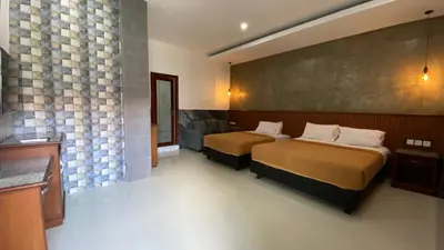 a hotel room with two beds and a wall at Sandat Hotel Legian in Legian