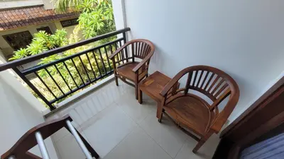 two benches sitting on a balcony looking out at a garden at Sandat Hotel Legian in Legian