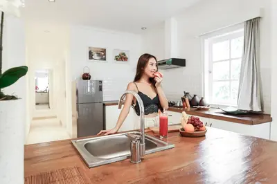 a woman standing in a kitchen talking on a cell phone at Umalas Suites in Seminyak