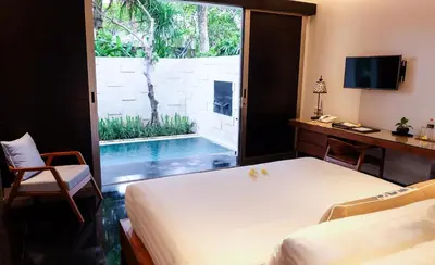 a room with a bed and a pool outside a window at Sun Island Boutique Villas & Spa Seminyak in Seminyak