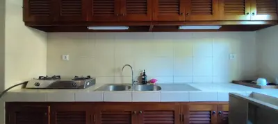 a kitchen with two stainless steel sinks and wooden cabinets at Villa Diana Bali in Legian