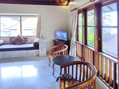 a room with a balcony with a table and chairs at Villa Diana Bali in Legian