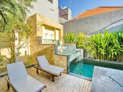 a patio with two chairs and a swimming pool at Villa Diana Bali in Legian