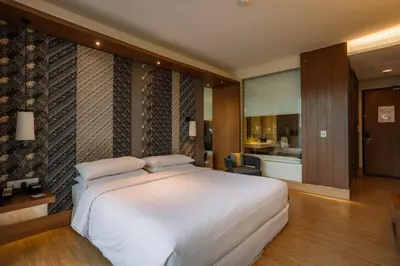 a bedroom with a large white bed and a bathroom at Four Points by Sheraton Bali, Seminyak in Seminyak