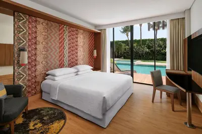 a bedroom with a bed and a tv and a pool at Four Points by Sheraton Bali, Seminyak in Seminyak