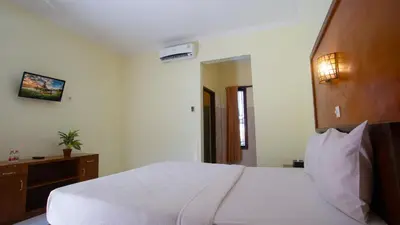 a bedroom with a large white bed with a wooden headboard at Teges Inn Kuta in Kuta