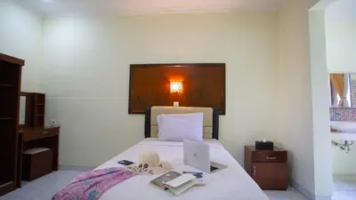 a bedroom with a bed with a laptop and books at Teges Inn Kuta in Kuta