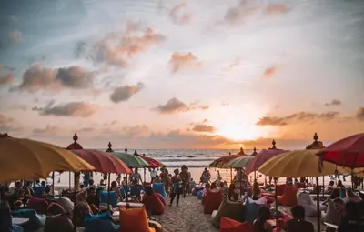 a crowd of people sitting on a beach with umbrellas at Teges Inn Kuta in Kuta