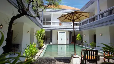 an indoor pool in a house with an umbrella at Teges Inn Kuta in Kuta