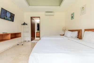 a bedroom with two beds and a tv on the wall at Villa Harmony Canggu in Canggu
