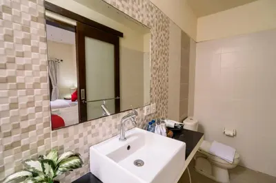 a bathroom with a sink and a mirror and a toilet at Taman Bali Villas Dewi Sri in Legian