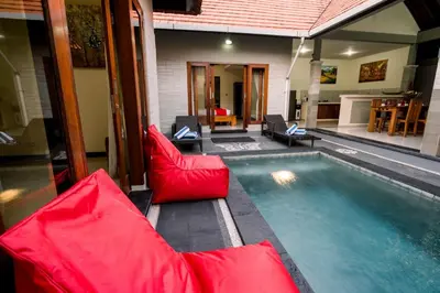 a pool with red furniture next to a house at Taman Bali Villas Dewi Sri in Legian