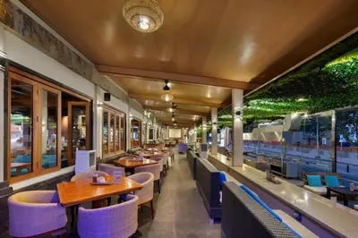a restaurant with wooden tables and chairs and windows at Grand Istana Rama Hotel in Kuta