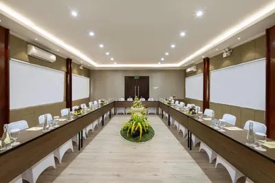 a conference room with long tables and white chairs at Grand Istana Rama Hotel in Kuta