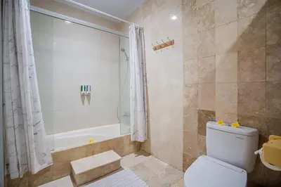 a bathroom with a shower and a toilet and a tub at Nipper Villa - Spacious 4BR in Canggu in Canggu