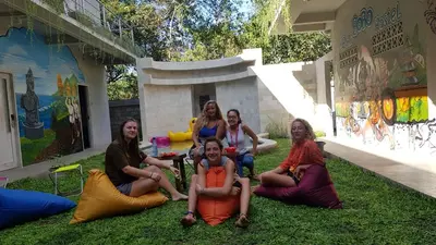 a group of women sitting on the grass in front of a building at Bali Bobo Hostel in Jimbaran