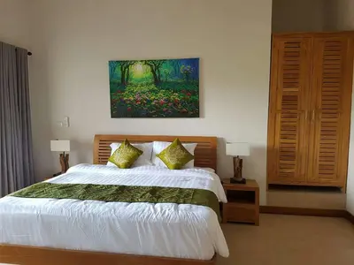 a bedroom with a bed and a painting on the wall at Villa Rahayu in Seminyak