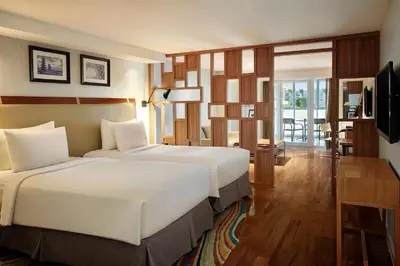 a hotel room with two beds and a television at The Kuta Beach Heritage Hotel - Managed by Accor in Kuta